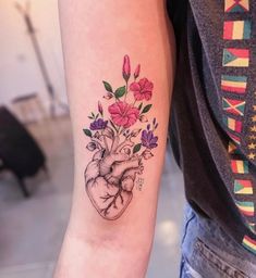 a heart tattoo with flowers on the arm