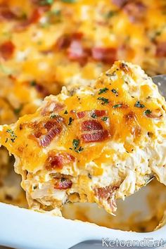 a spoon full of cheesy potato casserole with bacon and cheese on it