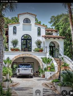 a truck is parked in front of a house with palm trees and stairs leading up to it