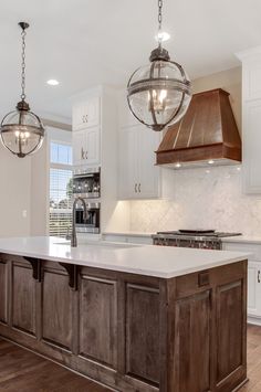 a kitchen with an island and two lights hanging from the ceiling