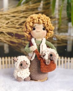 a crocheted doll is holding two lambs in her arms and wearing a scarf