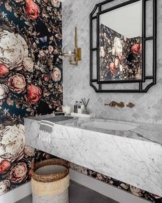 a bathroom with floral wallpaper and marble counter top, along with a round basket on the floor