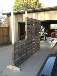 a car parked in front of a garage with a wooden fence on the side of it