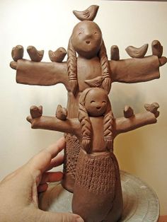 a person holding up a clay sculpture with birds on it's back and arms