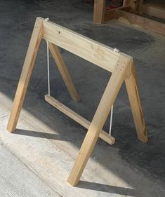 a wooden frame sitting on top of cement floor next to a table and chair in the background