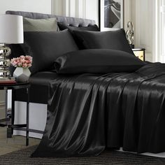 a bed with black sheets and pillows in a room