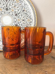 two brown glass mugs sitting on top of a wooden table