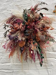 an arrangement of dried flowers on a white wall