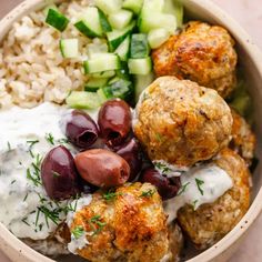 a bowl filled with meatballs, rice and cucumbers next to a salad