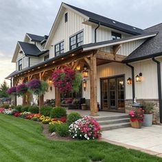 a large white house with lots of flowers on the front porch and landscaping around it