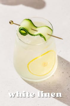 a white linen cocktail with lemon and cucumber garnish on the rim