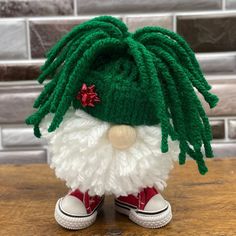 a close up of a stuffed toy with green hair and red shoes on a table