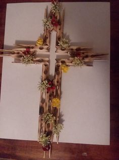 a cross made out of sticks with flowers on them sitting on top of a table