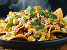 a bowl filled with nachos covered in cheese and sauce, garnished with cilantro