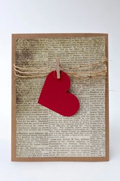 a red heart hanging from a string on top of a piece of paper