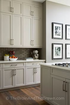 a kitchen with white cabinets and pictures on the wall above the stove top is filled with fruit