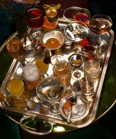 a tray filled with different types of glasses on top of a green tableclothed surface