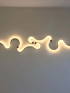 a wall with three lights on it and one light in the shape of a snake