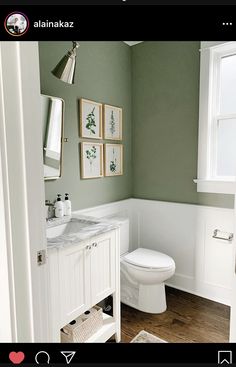 a white toilet sitting next to a sink in a bathroom under two pictures on the wall