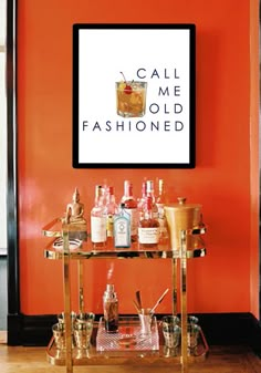 a bar cart with liquor bottles on it in front of an orange wall that says celebrate the little things