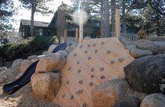 an outdoor play area with rocks and a slide