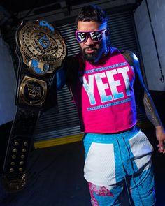 a man in pink shirt holding up a wrestling belt