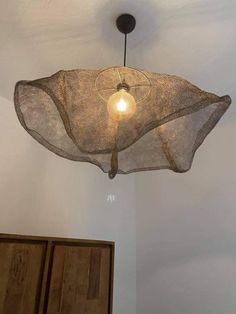 a light fixture hanging from the ceiling in a room with white walls and wooden cabinets