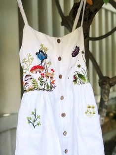 You love mushroom? Me too. I was filled of joy when I emberoidered this dress.   ❤ It's a lovely dress like a mini forest with colourful embroidered mushroom, flowers, strawberry, butterfly and bee motifs. - Material: linen, coconut button, hand embroidery. - Environmentally friendly. - This dress is very useful, go with any outfit, that can be used to go to school, go out, go shopping.    It is a perfect gift for yourself or your beloved.  ❤ Care instructions:      The best way to wash embroidery cloth is to put it in soapy water (with a mild detergent and cold water at 86 ºF/30oС) for 20 minutes. Try to not wash the item with other clothing that might cause damage, such as zippers, buttons or different colors. You wash it by hand, and if you have dirty patches on your garment, you can ge Embroidered Dress Diy, Strawberry Butterfly, Dress Hand Embroidery, Mini Forest, Simple Frocks, Hand Embroidery Dress, Go To School, Quick Outfits, Embroidered Clothes