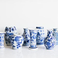 several blue and white vases are lined up on a table with an owl figurine in the middle