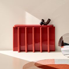 a red cabinet sitting on top of a white floor next to a mirror and lamp