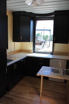 an empty kitchen with black cabinets and white counter tops is seen in this image from across the room