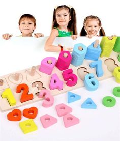 two children holding up a sign with numbers and shapes on it, while another child looks at the camera