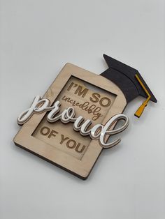 a wooden plaque that says i'm so incredibly proud of you with a graduation cap on top