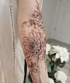 a woman's arm with black and white flowers on the left side of her arm