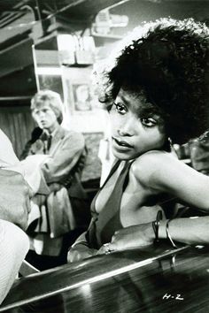 an old black and white photo of a woman sitting at a piano with other people in the background