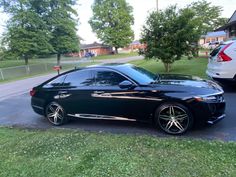 a black car parked on the side of a road next to a white car with chrome rims