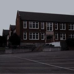 an empty parking lot in front of a large brick building