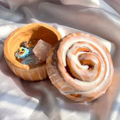 two glazed donuts with frosting in an open container on a white cloth covered tablecloth