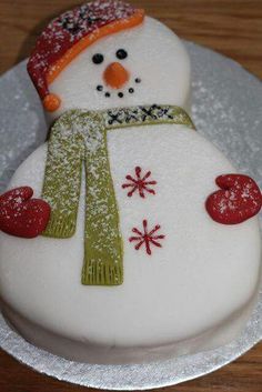 a frosted snowman cake sitting on top of a white plate