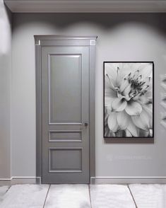 an empty room with a gray door and black and white flower painting on the wall