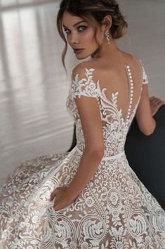 a woman in a wedding dress sitting on the floor with her back to the camera