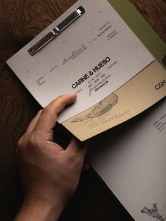 a person holding a piece of paper next to a clipboard on a wooden table