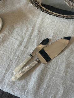 a pair of black and white utensils sitting on top of a cloth covered table