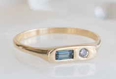 a close up of a ring on a white surface with a blue stone in the middle