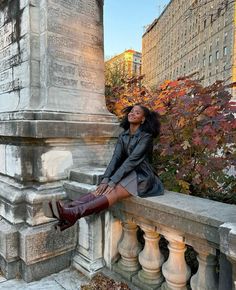 a woman sitting on top of a stone pillar