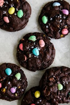 chocolate cookies decorated with candy eggs and m & m's on a white surface