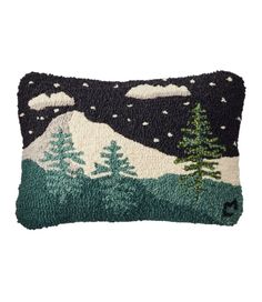 a decorative pillow with trees and snow on the mountain in the background, it is made out of knitted material