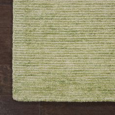 a green rug on top of a wooden floor with an area rug in the middle