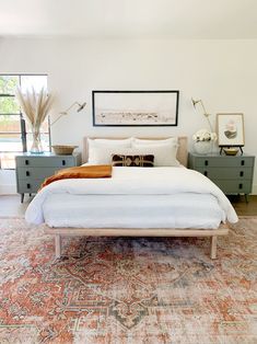 a bedroom with a large bed, dressers and pictures on the wall above it