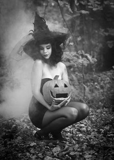 a woman dressed as a witch holding a pumpkin